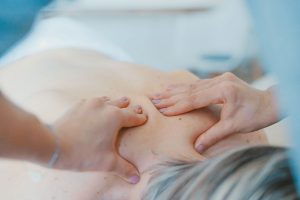 Manos haciendo tratamiento de fisioterapia en Barcelona en espalda de mujer tumbada